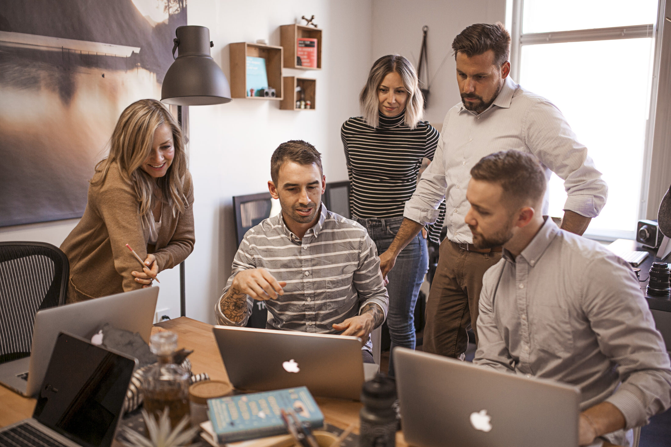web agency team collaborating around one macbook